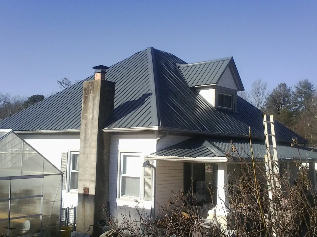 Dark blue standing seam metal roof on a white farmhouse with dormer — Slate & Tile Roof Repair by Roofing Brothers in Amargosa Valley