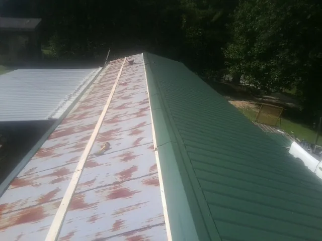 Old rusted panels beside newly installed green metal roofing — Wind Damage Roof Repair by Roofing Brothers in Amargosa Valley
