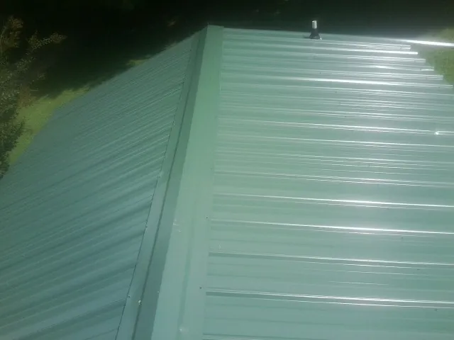 New green metal panels meeting at the ridge of a roof — Flat Roof Repair work by our crew in Amargosa Valley