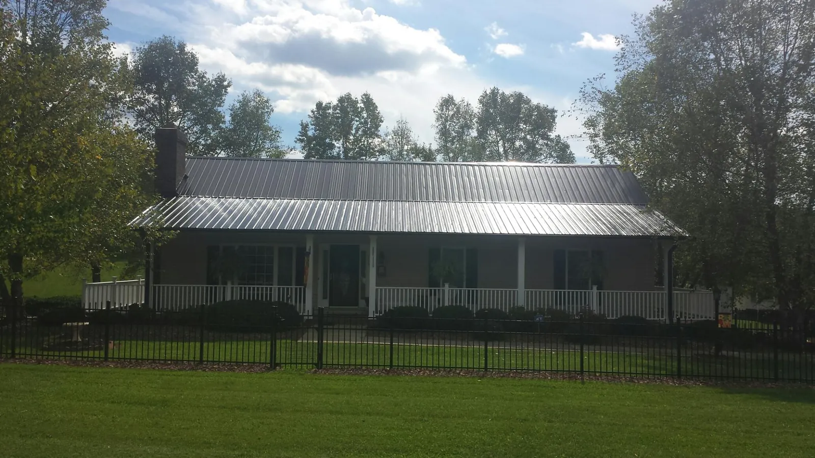 Gray metal roof on a brick ranch with a full width front porch — Gutter Guard Installation work by our crew in Amargosa Valley