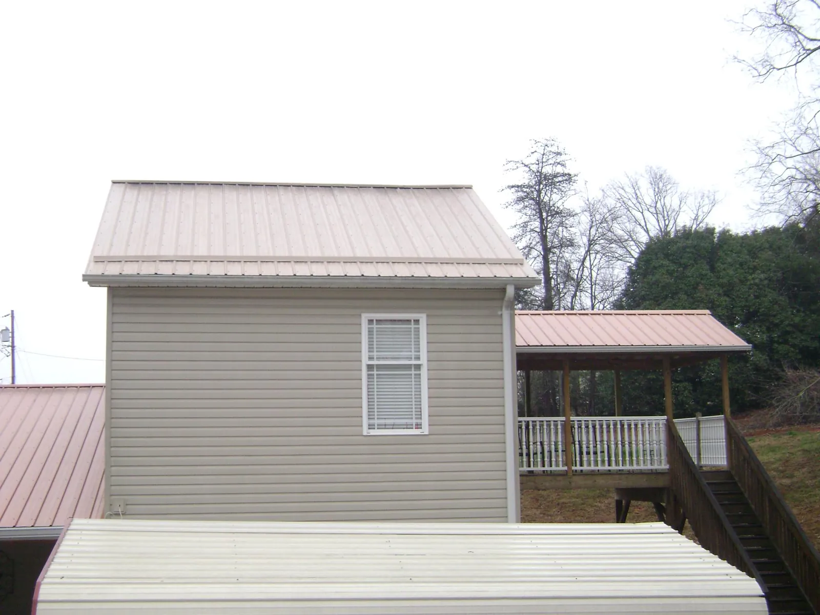 Tan metal roofs on a two story addition and attached porch, from a Roof Replacement job in Amargosa Valley