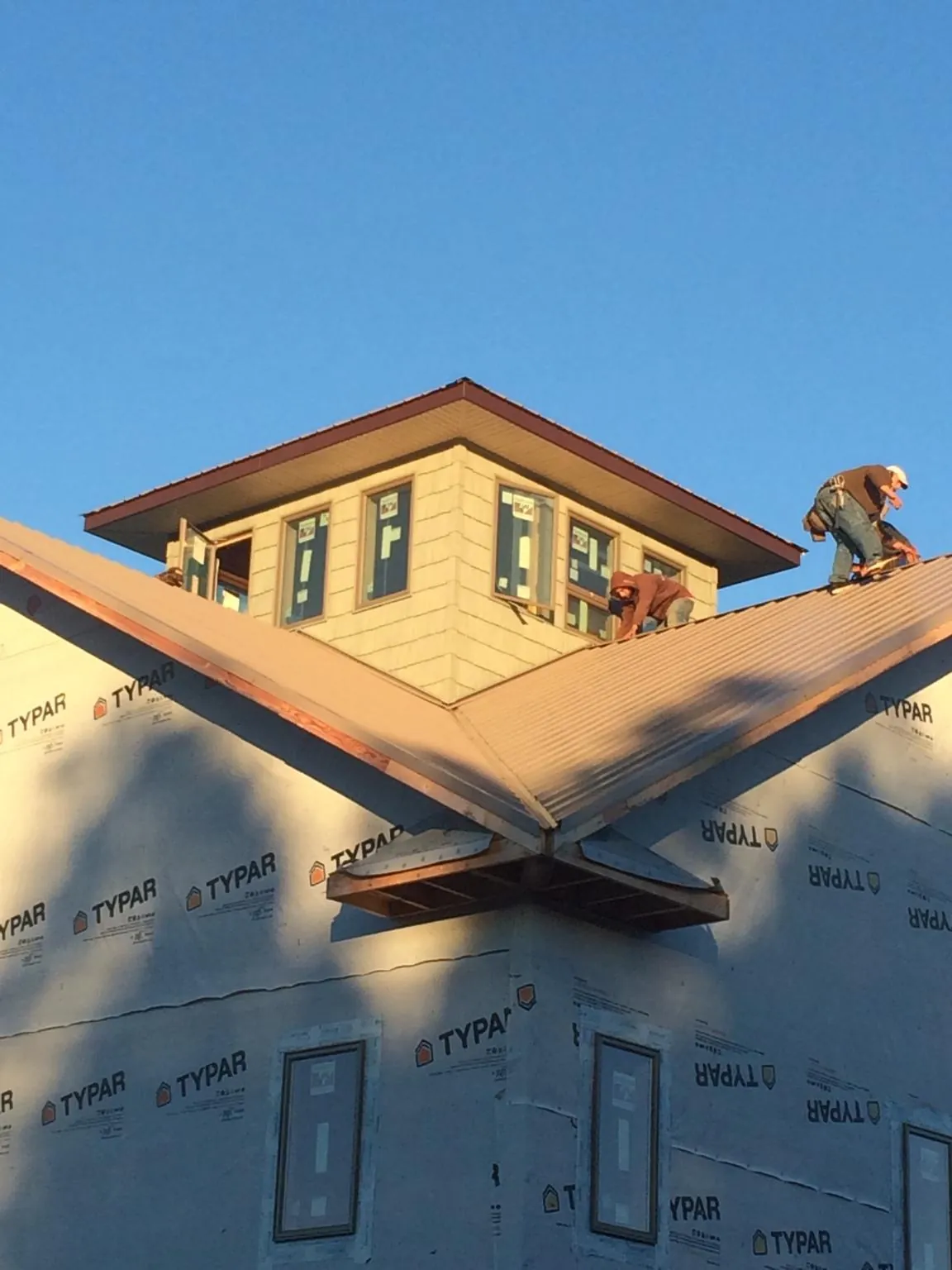 Roofers working around a rooftop cupola on a new metal roof at sunset — Roof Waterproofing in Amargosa Valley by Roofing Brothers